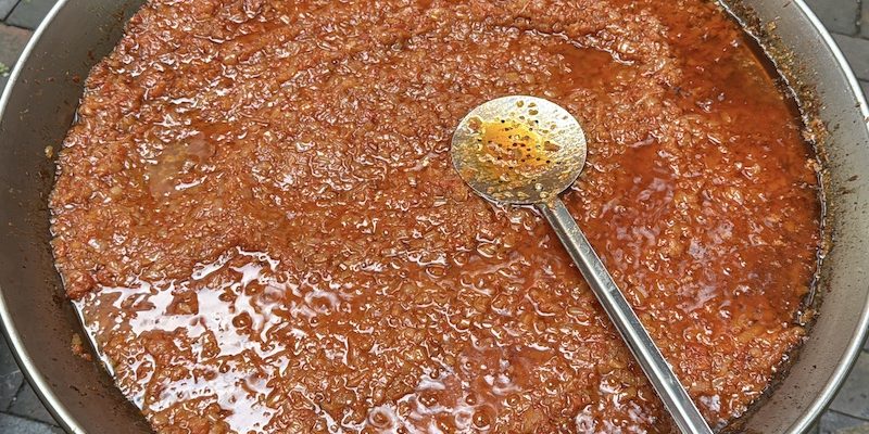 Slow-cooked sofrito in copper pan with wooden spoon
